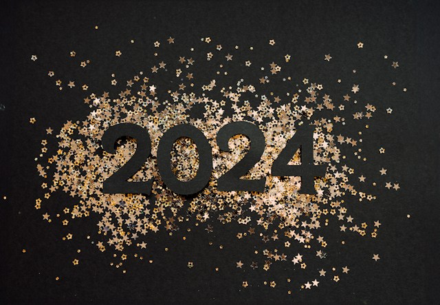 photo from unsplash.com of gold confetti on a black background that spells the year 2024